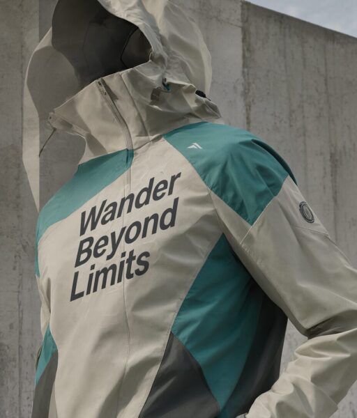 Urban Explorer Jacket Urban explorer jacket in beige and teal with 'wander beyond limits' slogan on shoulder, against concrete wall.