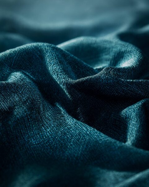 Cascading Blue Mesh Fabric Cascading blue mesh fabric with textured weave, captured in soft lighting against a blurred background.