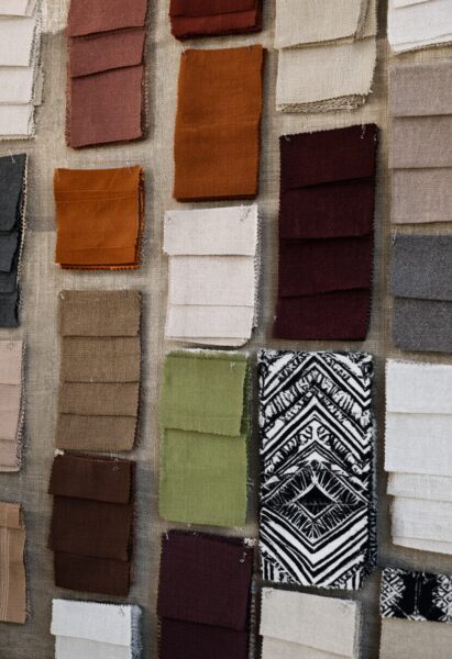 Colorful Fabric Swatches Display A collection of colorful fabric swatches in earth tones, greens, and a black-and-white patterned textile arranged on a textured background.