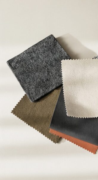 Textured Fabric Swatches In Soft Earth Tones Five textured fabric swatches in earthy tones including gray, beige, olive, black, and rust arranged on a neutral background.