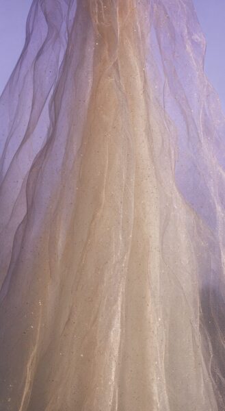 Golden Silk Draped Elegance Golden silk fabric gracefully draped, featuring subtle glitter particles, set against a soft lavender backdrop.