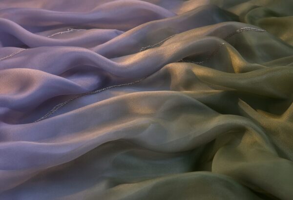 Elegant Draped Silk In Earth Tones Elegant draped silk fabric in soft lavender and olive green earth tones, showcasing luxurious texture and gentle waves.