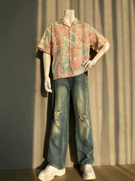 Sunlit Coastal Casual Ensemble Mannequin in sunlit room wearing coral-green floral shirt, ripped wide-leg jeans, and chunky white sneakers.