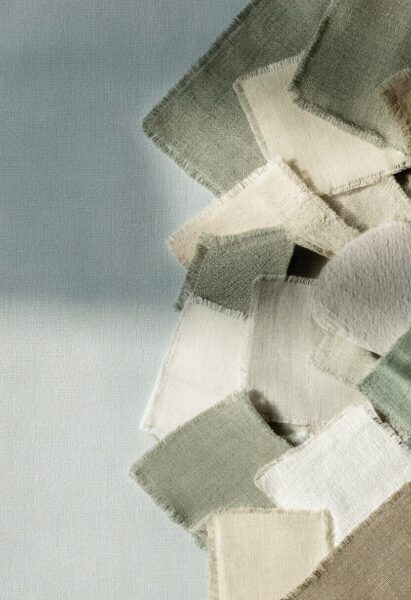 Soft Textured Fabric Swatches Soft textured fabric swatches in muted greens, creams, and beige tones arranged diagonally against a light gray background.