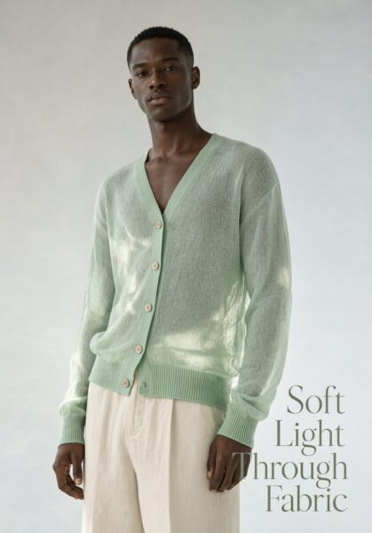 Semi-Sheer Mint Cardigan With Cream Pants A man wears a semi-sheer mint cardigan over cream pants under soft studio lighting.