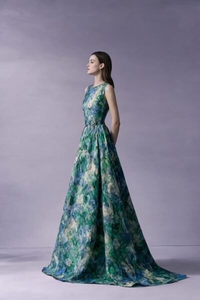 Elegant Garden Bloom Gown A woman in an elegant floor-length floral gown with green, blue, and white hues stands against a soft lavender background.