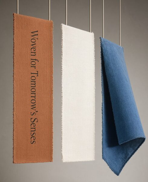 Three Hemp Swatches Draped Elegantly Three hemp fabric swatches in terracotta, cream, and blue hang elegantly against a soft gray wall.