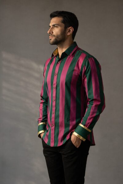 Confident Man In Bold Stripe Shirt Confident man wearing bold vertical striped shirt with green and magenta stripes, standing against gray background.