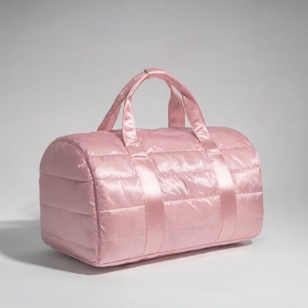 Soft Pink Quilted Duffle Bag A soft pink quilted duffle bag with satin handles, photographed in a minimalist studio setting.