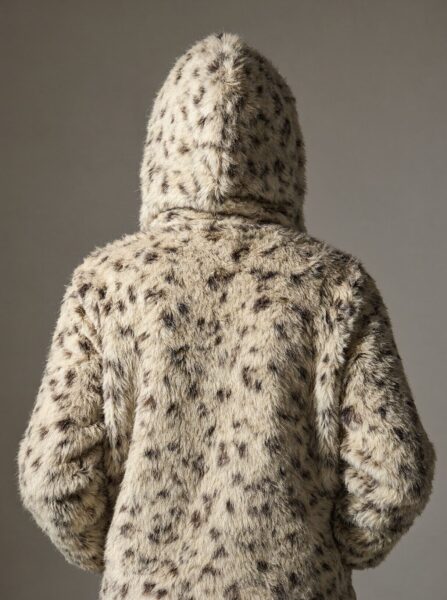 Faux Fur Hoodie Back View Back view of a person wearing a spotted faux fur hoodie with hood up against neutral background.